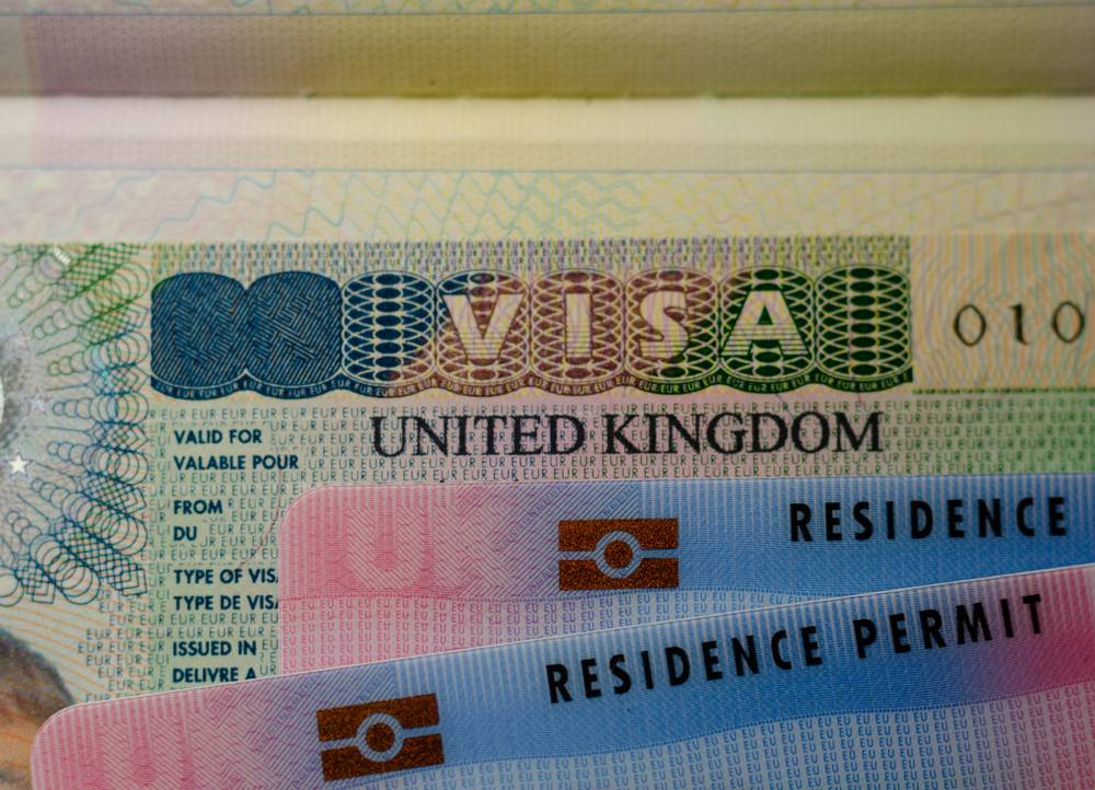 Jobs that can get you a UK Visa: UK BRP (Biometrical Residence Permit) cards for Tier 2 work visa placed on top of UK VISA