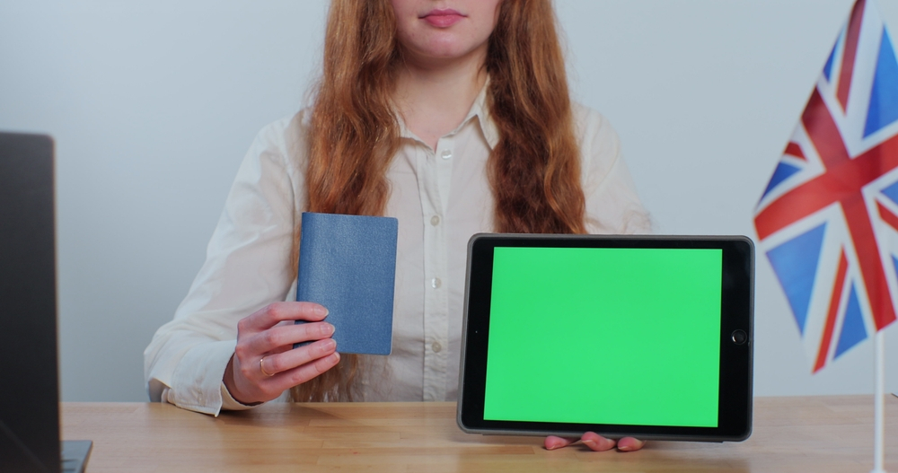 Things to Avoid During the UK Visa Application Process: A picture showing a visa applicant displaying passport and tab for application process.