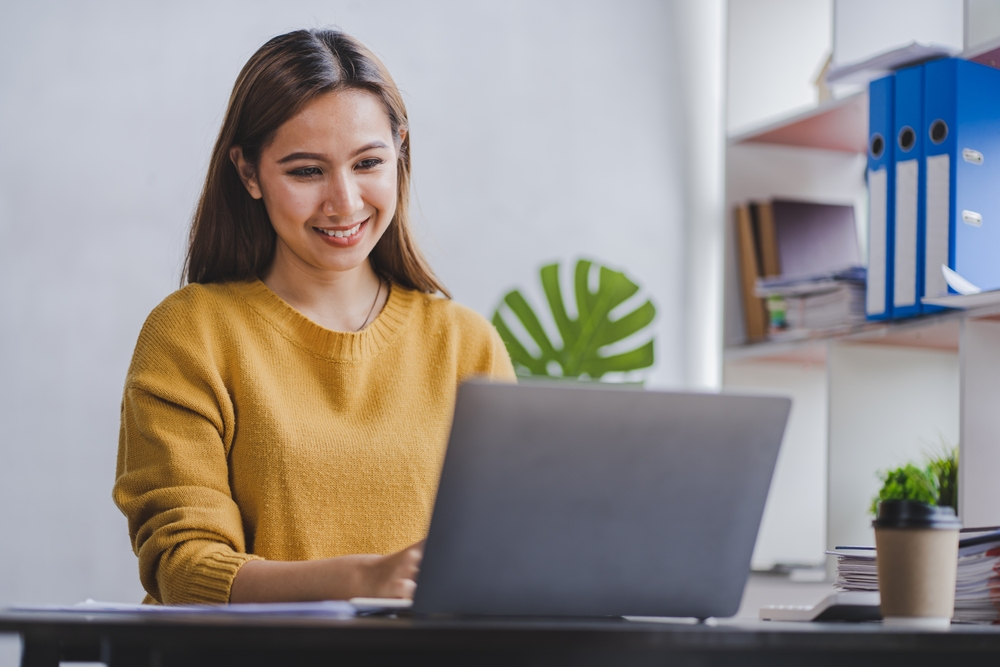 Remote job at Buffer: A happy female freelancer working on a laptop at home office