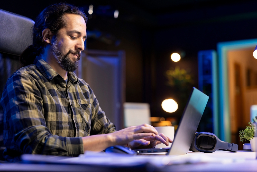 The Ultimate Guide to Setting Up a Productive Home Office: Picture of a man using a laptop to type and browse the internet at his living room desk. 