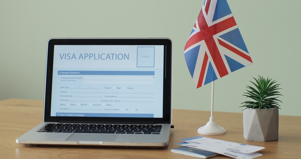 How to avoid UK visa scams: Online United Kingdom Visa Application showing on a laptop computer screen sitting on a desk.