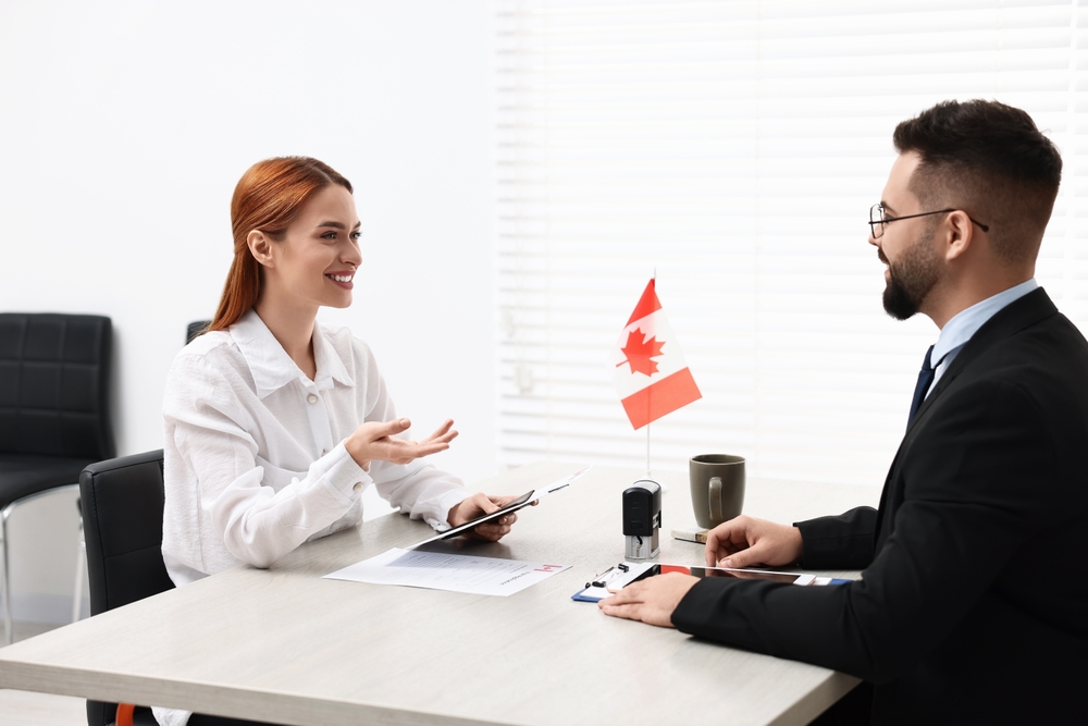 Things to Avoid on Your Canada Visa Application: Smiling woman having interview with embassy worker in office